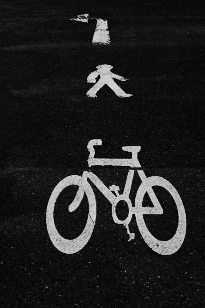 Artistic black and white photo showing road signage for bicycle and pedestrian path.